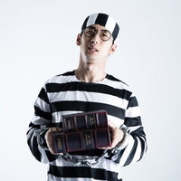 同じ本のハードカバーと文庫本を購入するハロウィン囚人コスプレの男性の写真