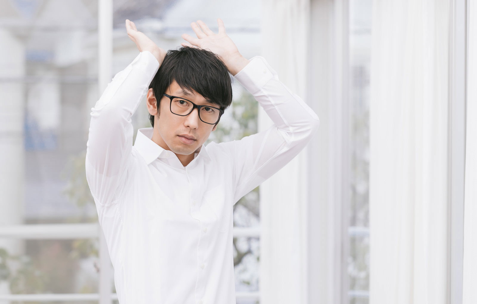 眼鏡の男性が両手を頭上に上げるポーズ［モデル：大川竜弥］