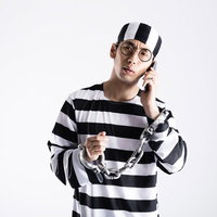 鍵の110番に電話をする囚人コスプレ男性の写真