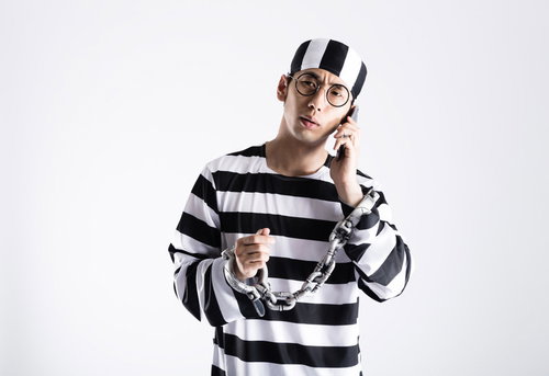 鍵の110番に電話をする囚人コスプレ男性