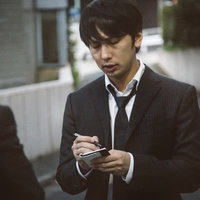 犯行現場付近で聞き込み取材をする若手記者が手帳にメモを取るの写真
