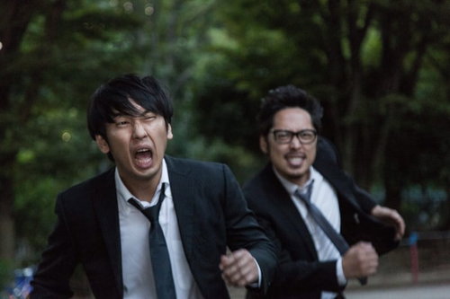 全力で容疑者を追いかけるスーツ姿の男性記者