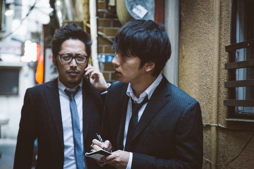 夜間の街で聞き込み取材する操作委員と記者