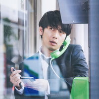 取材中に電話ボックスで通話する編集者・ジャーナリストの写真