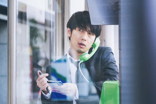 取材中に電話ボックスで通話する編集者・ジャーナリスト