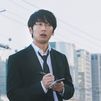 都会でスマートフォンを手に情報確認するジャーナリスト男性の写真