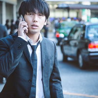 出張帰りタクシーを呼び出しながら待つビジネスマンの写真