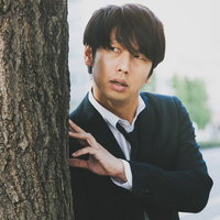 樹の幹に身を隠して尾行する調査員の浮気調査の写真