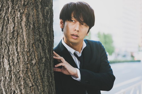 樹の幹に身を隠して尾行する調査員の浮気調査