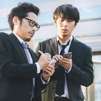 取材先での情報をメモに取るジャーナリストと男性の写真