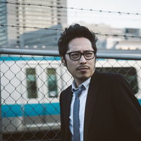 駅前で張り込み調査するジャーナリスト、スーツ姿の男性記者の写真