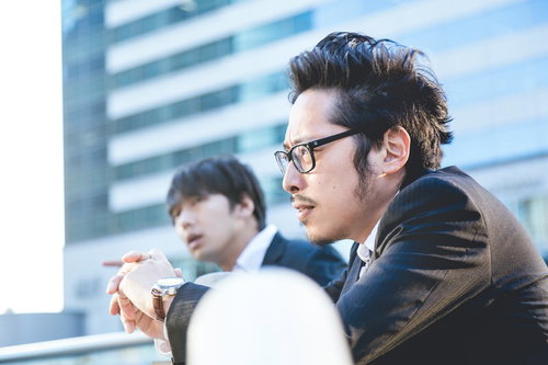 昔の武勇伝を語る営業部の先輩とビルの前での営業マン