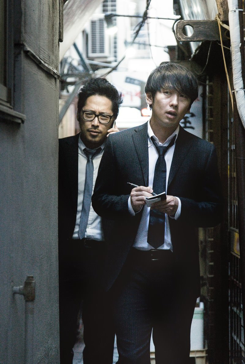 路地裏で取材中の記者とジャーナリスト。右側の男性がメモ帳に記録している［モデル：ゆうせい 大川竜弥］