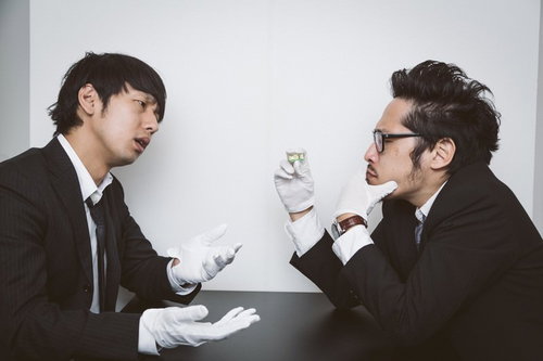 怪しい錠剤を調べる刑事と記者が証拠を確認