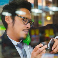 公衆電話で通話しながら自分で書いたメモが読めない男性の写真