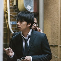 公衆電話で聞き込み捜査を行う刑事の写真