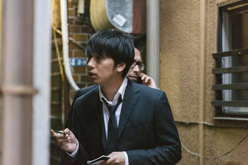 公衆電話で聞き込み捜査を行う刑事