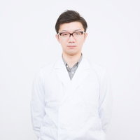 正面を向いて立つ眼鏡をかけた白衣のドクターの写真