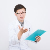 バインダーを持って手を上げる白衣の男性の写真