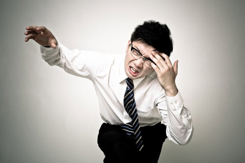 額に手を当て右手を伸ばす頭痛顔の眼鏡の会社員