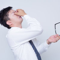 眼球疲労で目をおさえるビジネスマンの写真