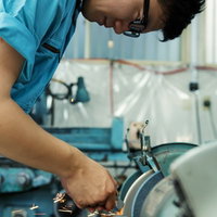 研磨機で金属を削り火花を散らす作業員の写真