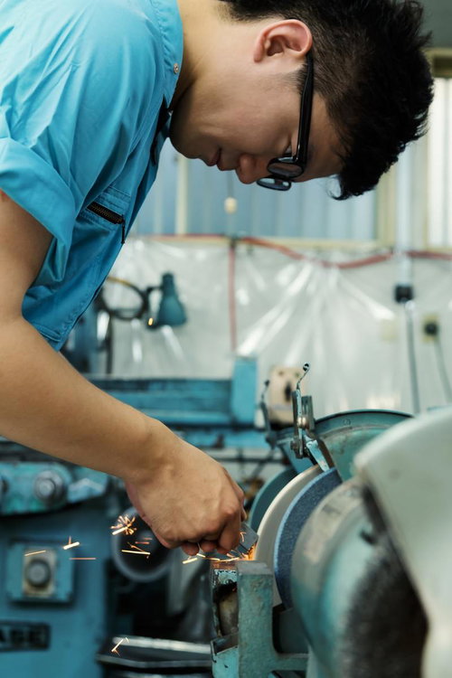 研磨機で金属を削り火花を散らす作業員