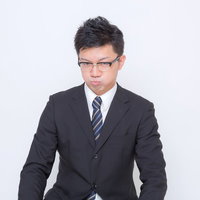 頬をふくらませるスーツの眼鏡の男性の写真
