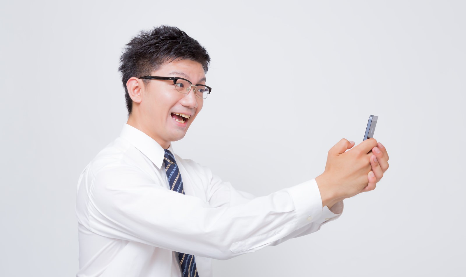 白いワイシャツ姿でスマートフォンを構えて自撮りするビジネスマン［モデル：OZPA］