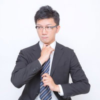 顎に手を当てて考える眼鏡のビジネスマンの写真