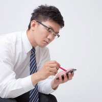 スタイラスペンを持ちスマホを操作するビジネスマンの写真