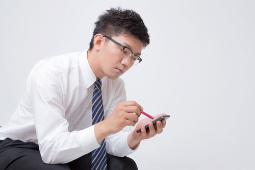 スタイラスペンを持ちスマホを操作するビジネスマン