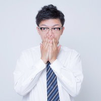 両手で顔を覆って驚くビジネスマンの写真