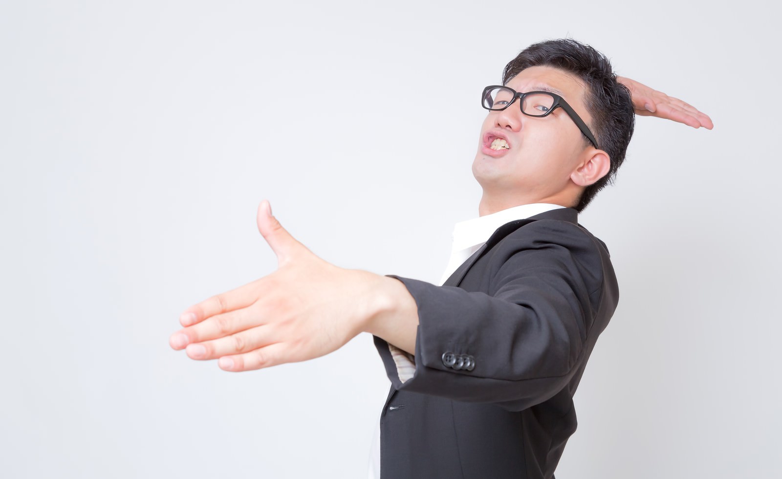 両腕を前に伸ばして上を向くスーツの眼鏡の男性［モデル：OZPA］