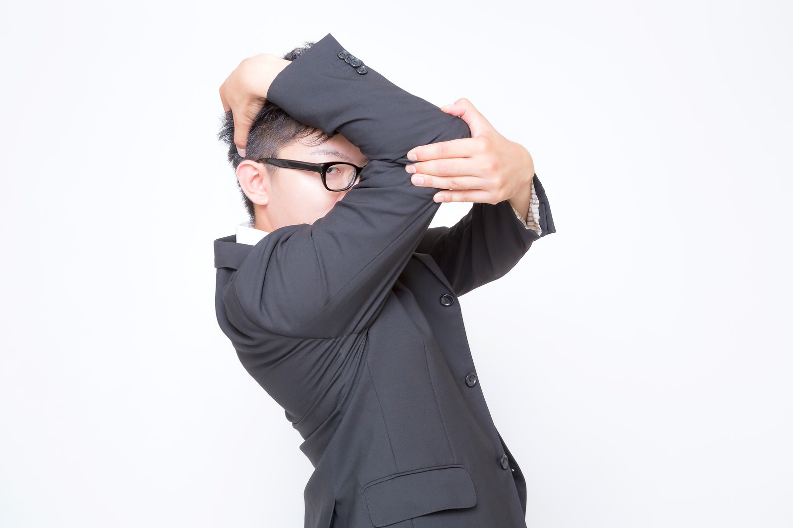上着を頭の上にかざすスーツの眼鏡の男性［モデル：OZPA］