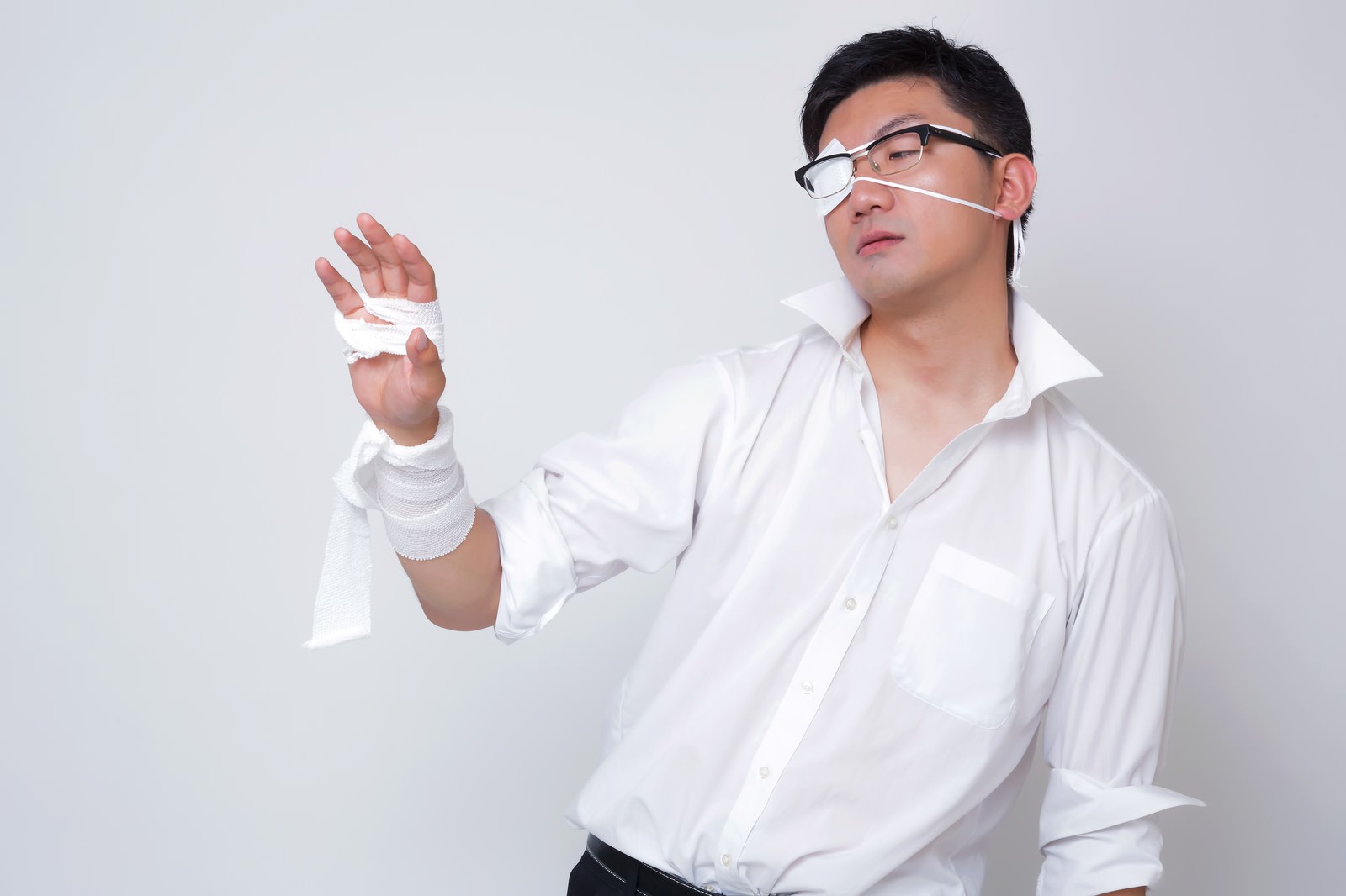 眼帯と包帯を巻いた男性が両手を広げて激怒し、上方を見つめている［モデル：OZPA］