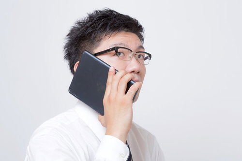iPadを電話機として耳に当てるサラリーマン