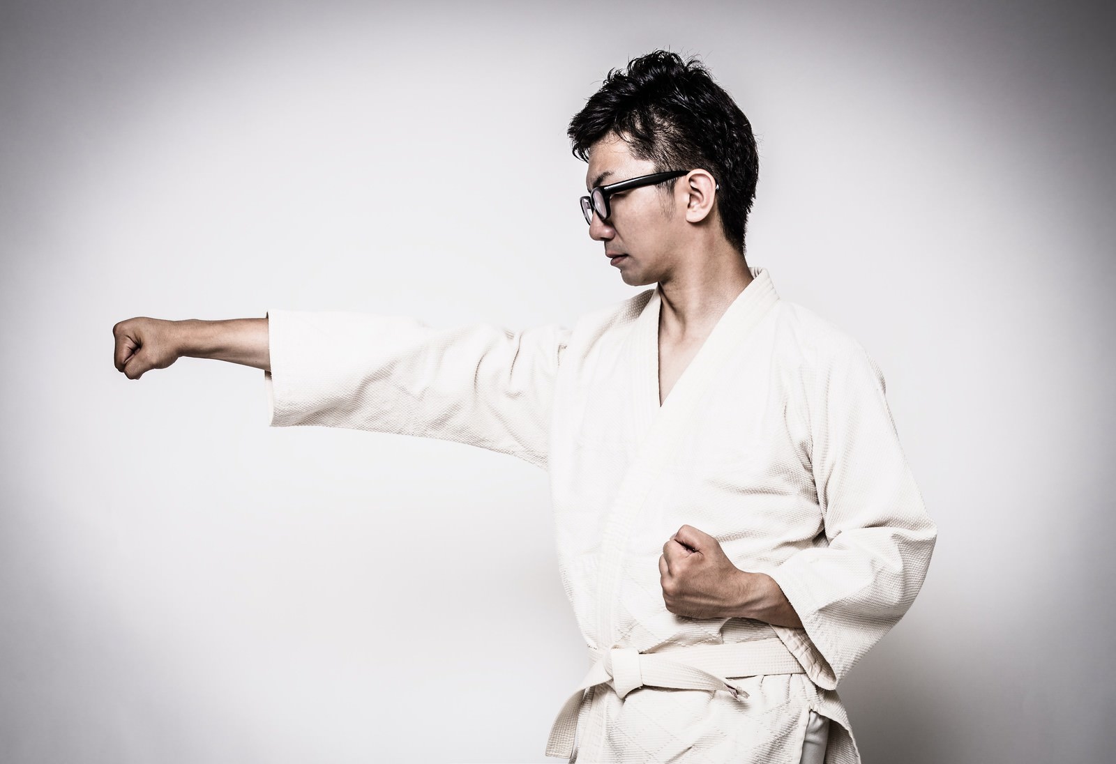 道着姿で正拳突きをする眼鏡の男性［モデル：OZPA］