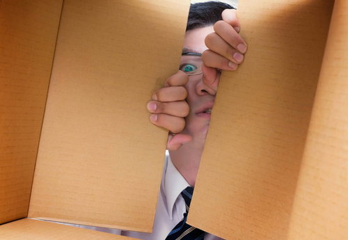 ダンボールの隙間から覗く男性の顔