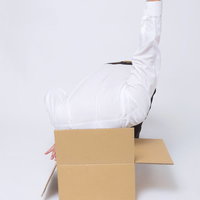 ダンボールに吸い込まれるシャツの男性の写真