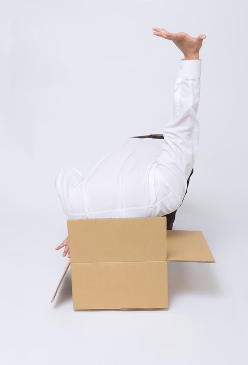 ダンボールに吸い込まれるシャツの男性