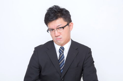 「おこ」な表情のスーツ姿の男性