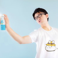 青いスプレー缶を右手で持ち上げる眼鏡の白Tシャツ男性の写真