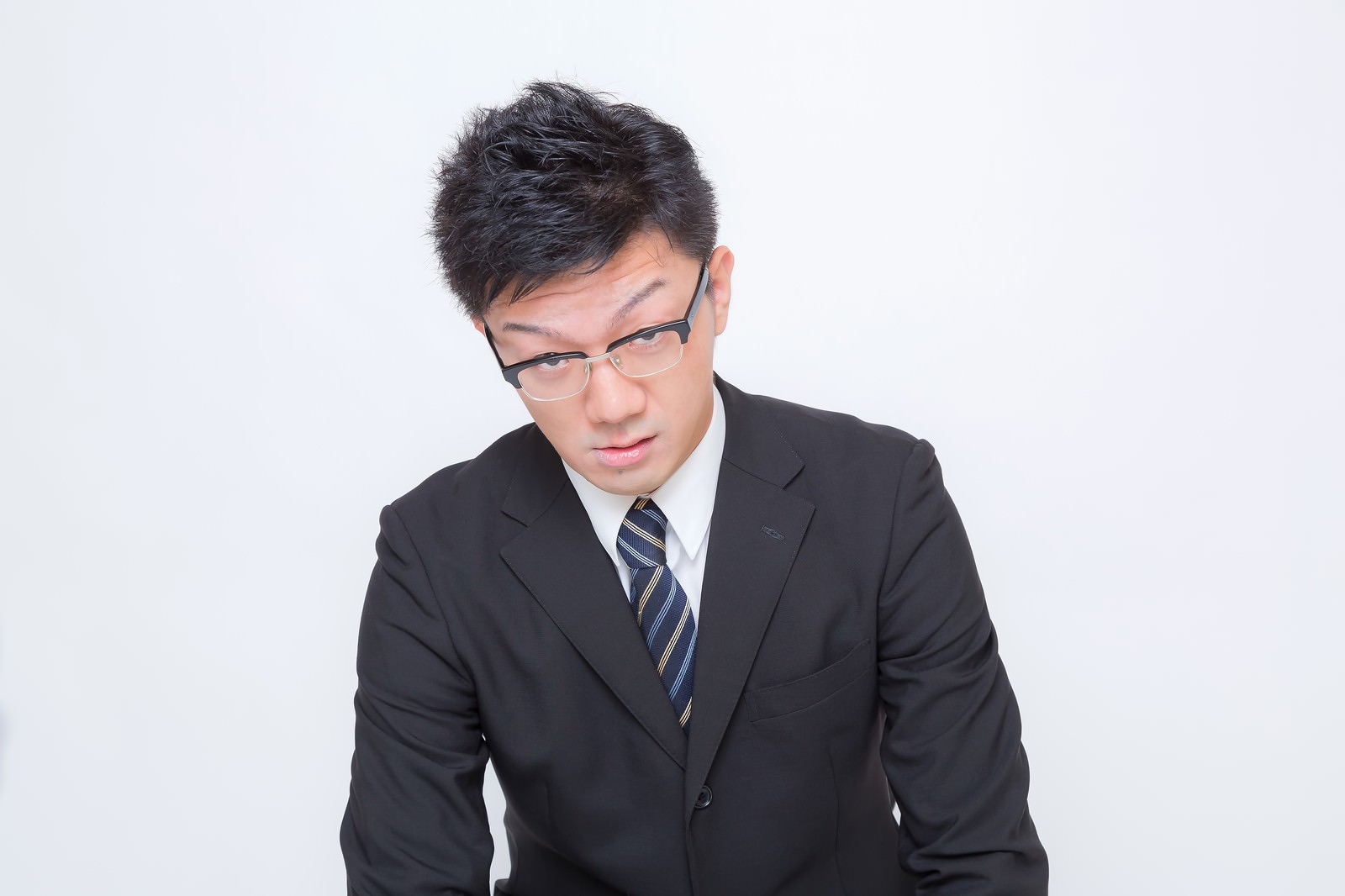 下を向くスーツ姿の眼鏡のサラリーマン［モデル：OZPA］