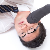 床に横たわりぐったりする眼鏡の男性の写真