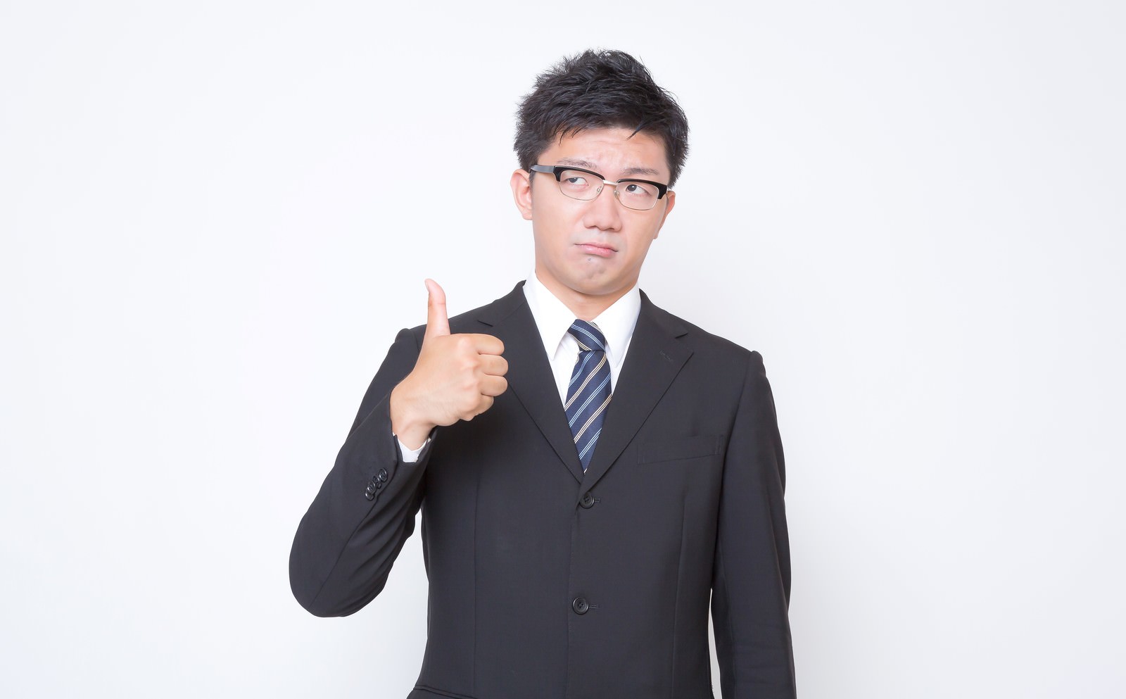 不満そうな表情で親指を立てる眼鏡のサラリーマン［モデル：OZPA］