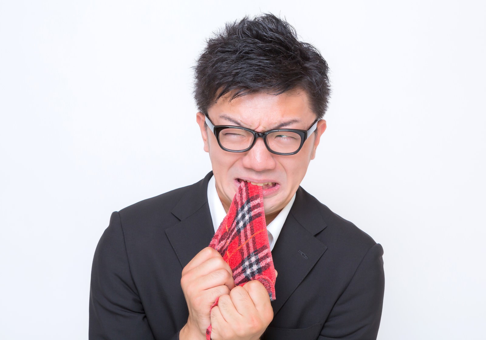悔しくてチェック柄のハンカチを噛む眼鏡の男性［モデル：OZPA］