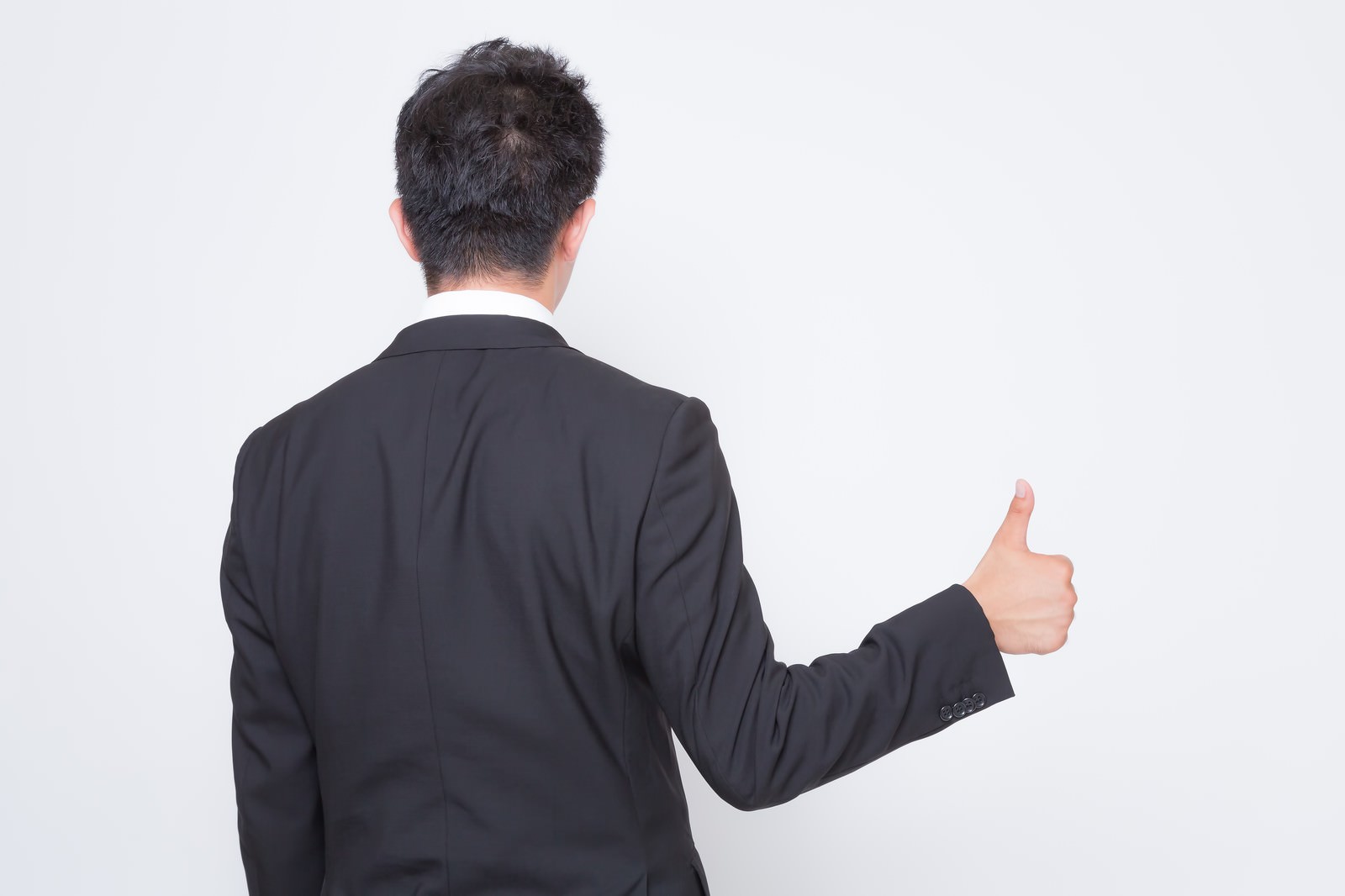 後ろ向きで親指を立てるスーツ姿の男性［モデル：OZPA］