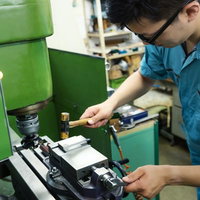 フライス盤を操作する水色の作業服の男性の写真