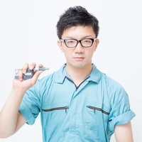 マイクロメーターを手にする作業服の男性の写真